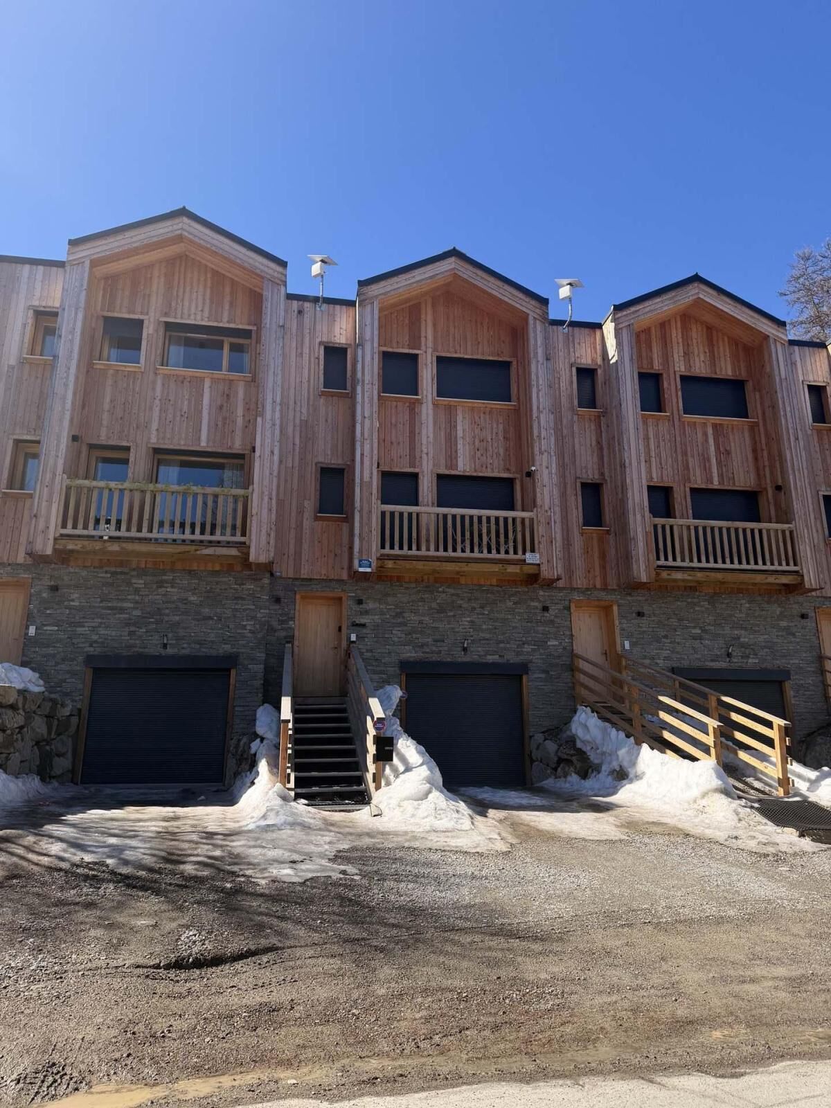 A multi-story building with wooden exterior walls, balconies, and garage doors.