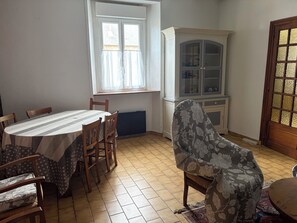 A dining area with a table, chairs, a cabinet, and a window. - Typical Breton stone house sleeping 1 to 8 people (Ploulec'h)