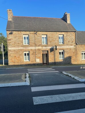 Un bâtiment en pierre de deux étages, doté d’une entrée centrale, de nombreuses fenêtres et d’une route pavée devant.