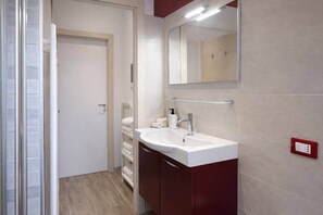 Ein Badezimmer mit einem weißen Waschbecken, einem Spiegel und einem Handtuchhalter.