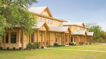 A multi-story building with a covered patio area and a well-maintained lawn.
