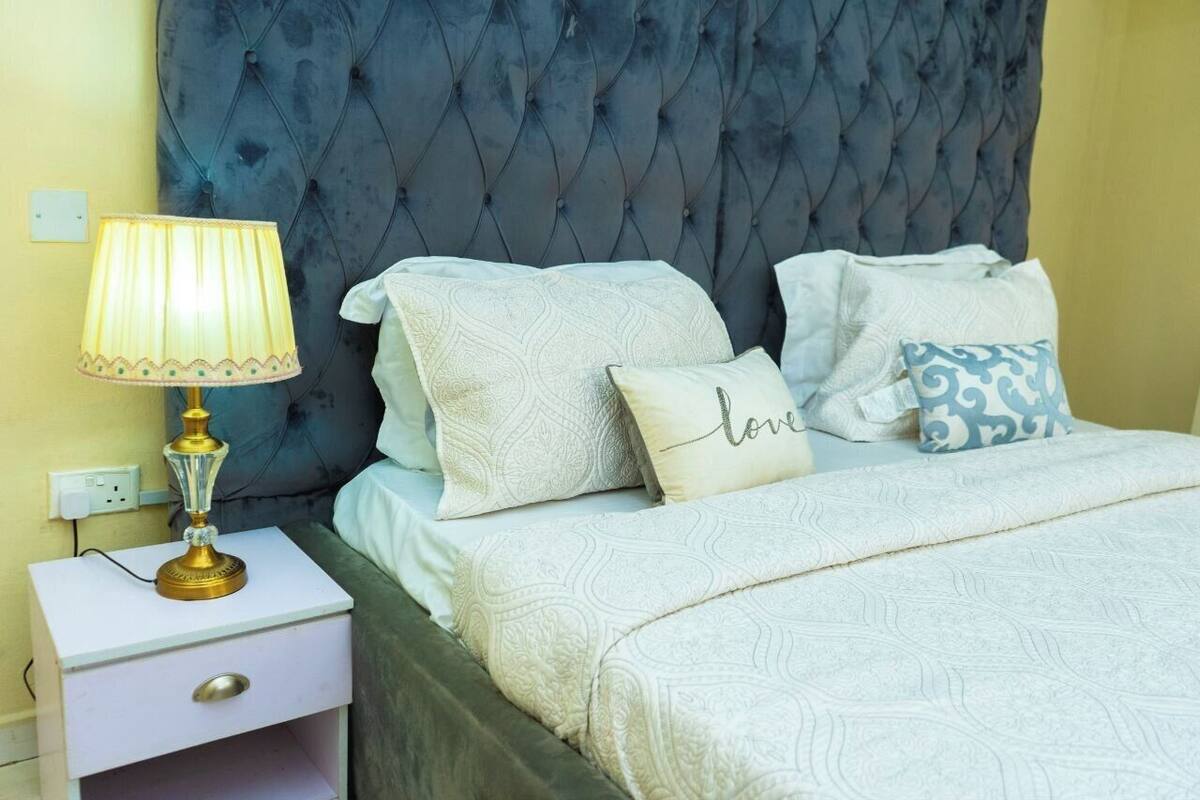 A bed with a tufted headboard, a bedside lamp, and patterned pillows.