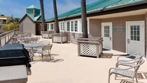 Un espace extérieur aménagé en terrasse, avec des palmiers, des sièges et un bâtiment doté d’un toit végétalisé.