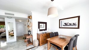 Un comedor con una mesa y sillas de madera, una lámpara colgante y un cuadro en la pared.