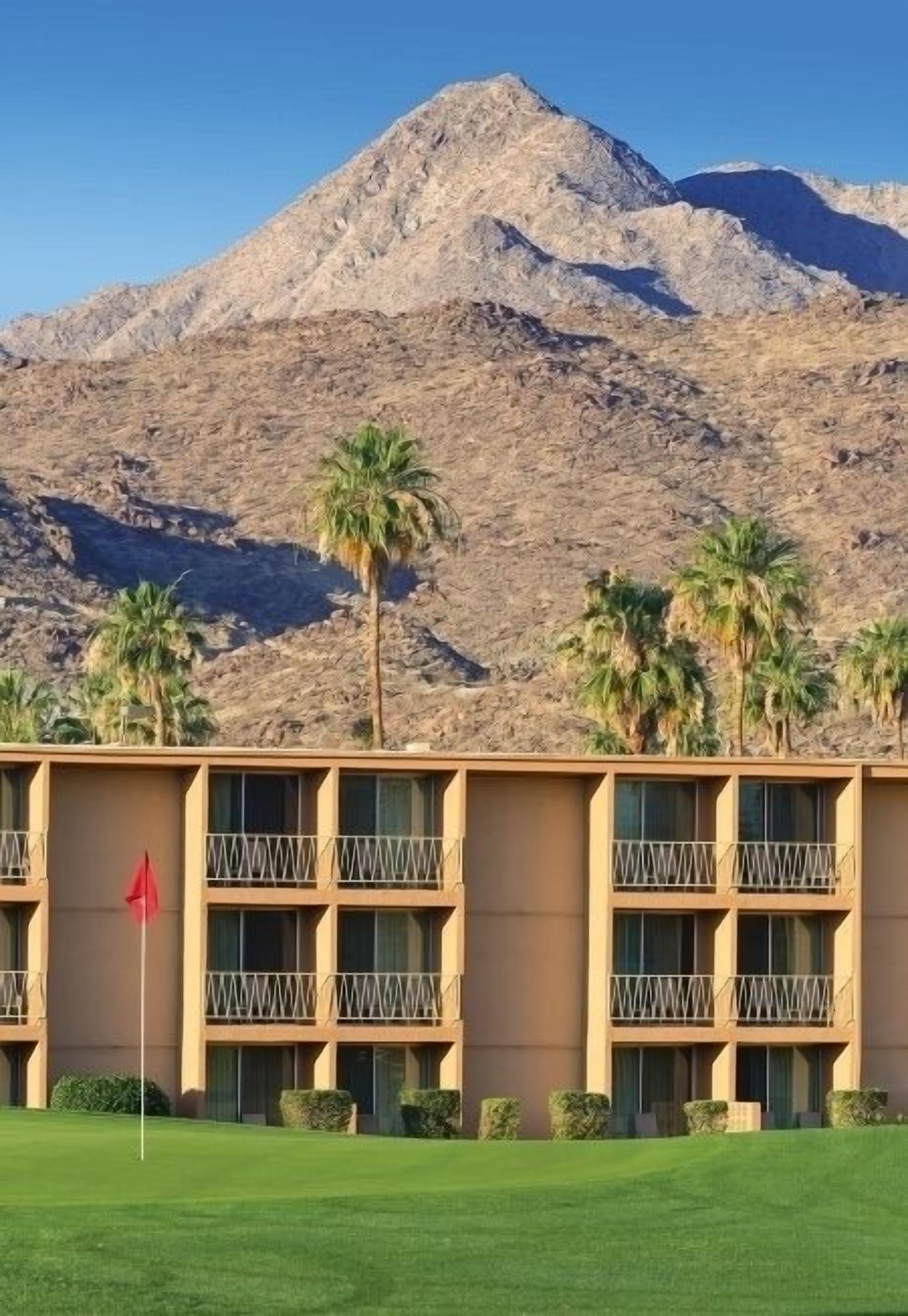 A hotel with a flat roof, multiple balconies, and a view of a mountain.