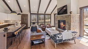 Una cocina moderna con barra, chimenea de piedra y televisor grande.