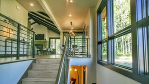 Un interior espacioso con una escalera, ventanas amplias y vistas al exterior.