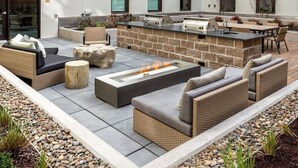 Eine Terrasse im Freien mit Feuerstelle, Sitzgelegenheiten und einer Bar.