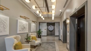 Un vestíbulo moderno con una recepción, dos sillones, una planta en maceta y un reloj de pared.