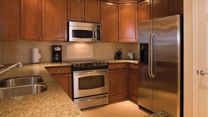 A kitchen with wooden cabinets, a stainless steel refrigerator, a microwave, a stove, and a sink. - Reunion | Upscale Golf Retreat | Pool + Golf | 3BR Sleeps 8 (Reunion)