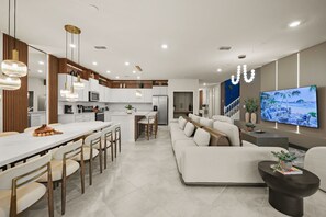 A modern kitchen with white cabinets, a central island, and pendant lighting. - 10 BD/ 8 BA/ Windsor Cay (1001 BP) (Clermont)