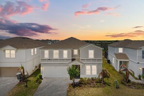 A residential area with houses, a driveway, and a grassy area with small trees. - 10 BD/ 8 BA/ Windsor Island Resort (2120 LC) (Davenport)