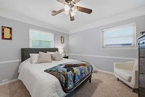 A bedroom with a bed, a ceiling fan, two windows with blinds, a dresser, and a nightstand with a lamp. - WinStar Getaway: 3 bedroom 2 full bath - Sleeps 6-10 - Lot of Parking - EV Port (Gainesville)