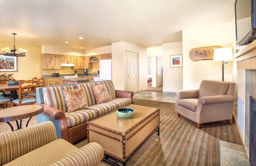 A living room with a sofa, armchairs, a coffee table, and a dining area with chairs and a table.