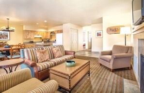 A living room with a sofa, armchairs, a coffee table, and a dining area with chairs and a table.