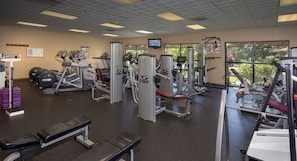 Une salle de sport équipée de machines de cardio, de matériel de musculation et de bancs.