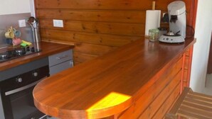 Una cocina con paneles de madera, una cafetera y un lavamanos pequeño.