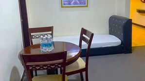 Una habitación con una mesa redonda, dos sillas, una cama, un equipo de aire acondicionado y un cuadro en la pared.