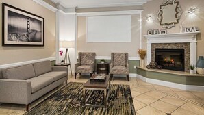 A living room with a sofa, two armchairs, a coffee table, a fireplace, a framed picture, and a decorative mirror. - San Francisco | Couples City Stay | Wi-Fi + Gym (San Francisco)