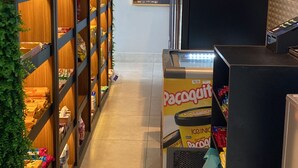 A corridor with shelves stocked with snacks and beverages, a vending machine, and a security camera. - Osasco-New Flat The Cityplex (Osasco)