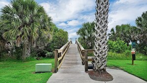 A wooden boardwalk leading through a park with palm trees and a pet waste sign. - Beachside Condo Resort Sleeps 6 in Beautiful St Augustine! (St. Augustine)