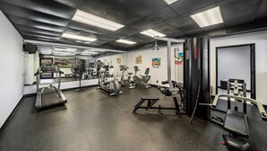 Een fitnessruimte met loopbanden, elliptische trainers en gewichten.