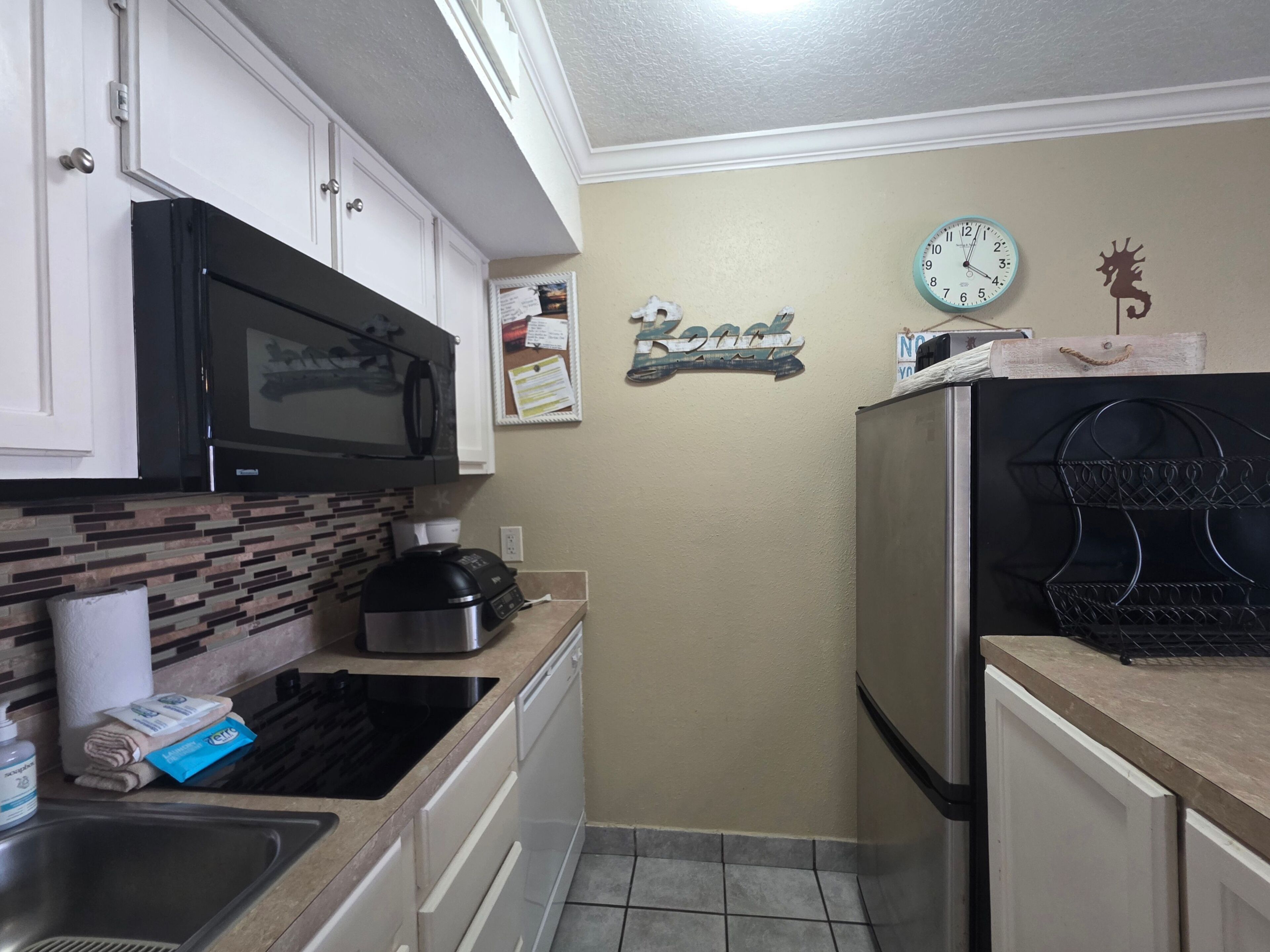 A compact kitchen with white cabinets, a microwave, a coffee maker, and a refrigerator.