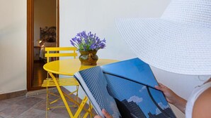 Iemand leest een tijdschrift aan een gele tafel met een bloempot.
