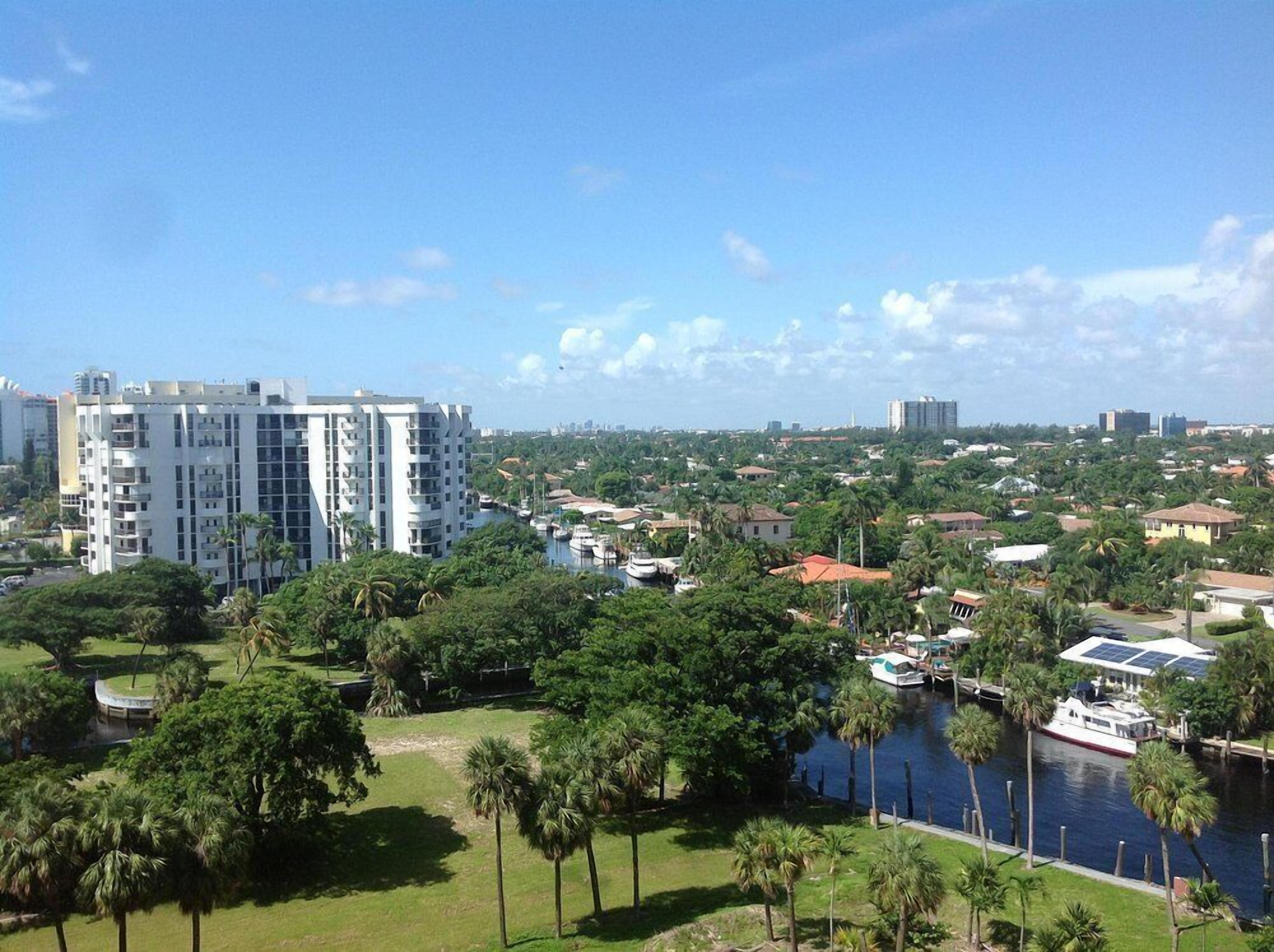Um edifício alto com vários andares, uma marina com barcos e um rio com vegetação.