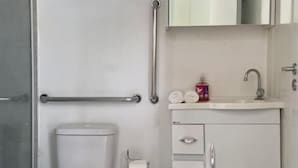Un baño con inodoro, lavamanos, espejo y cubo de basura.