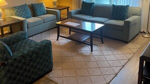 Una sala de estar con un sofá, dos sillones, una mesa de centro y una alfombra.