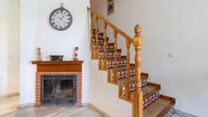 Un escalier avec des balustrades en bois et une cheminée encadrée de briques.