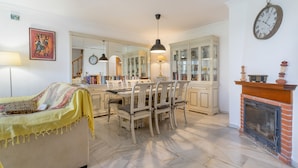 Un salon comprenant un canapé, une table à manger, des chaises, une cheminée et une horloge au mur.