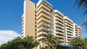 A multi-story hotel with a flat facade, balconies on each floor, and a clear blue sky. - Santa Barbara | Romantic Beach Retreat | Pool + Beach (Pompano Beach)