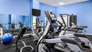 A gym with exercise equipment, a television, and a blue wall. - Santa Barbara | Romantic Beach Retreat | Pool + Beach (Pompano Beach)