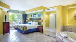 A hotel room with a bed, bedside table, lamp, and a view of the outdoors. - Santa Barbara | Group Beach Retreat | Pool + Beach | 2BR (Pompano Beach)