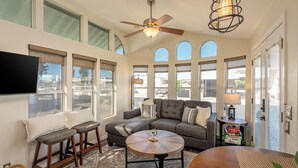 A spacious living room with a grey sectional sofa, a round coffee table, and a ceiling fan. - Live on Island Time on Beachcomber Blvd, Lake Havasu City (Lake Havasu City)
