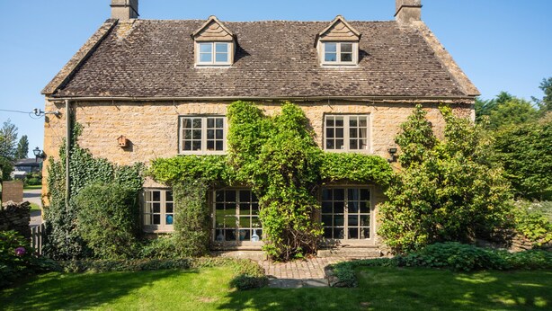A stone house with a tiled roof, two chimneys, and a garden with a lawn and shrubs. - Cottage Sleeps 6 With Parking and Garden (Shipston on Stour)