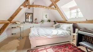A bedroom with a sloped ceiling, a bed, a desk, a chair, and a window. - Cottage Sleeps 6 With Parking and Garden (Shipston on Stour)