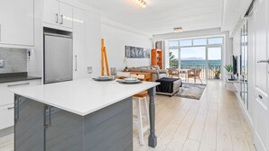 Una cocina moderna con una isla grande, un comedor con vistas y un espacio de sala de estar con sofá y mesa de centro.