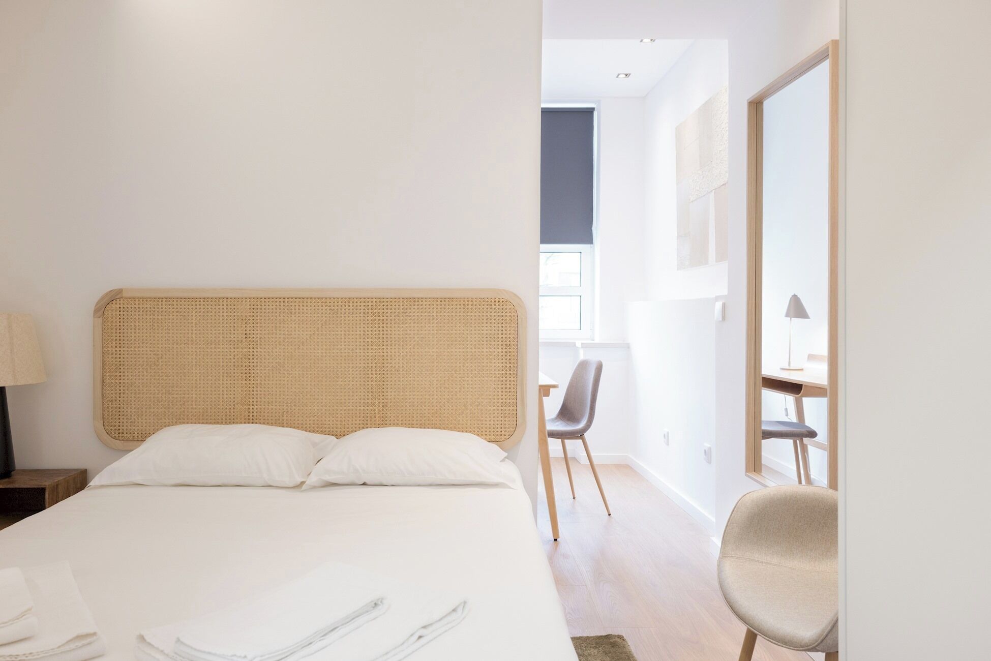 A hotel room with a large bed, a desk, and a chair.
