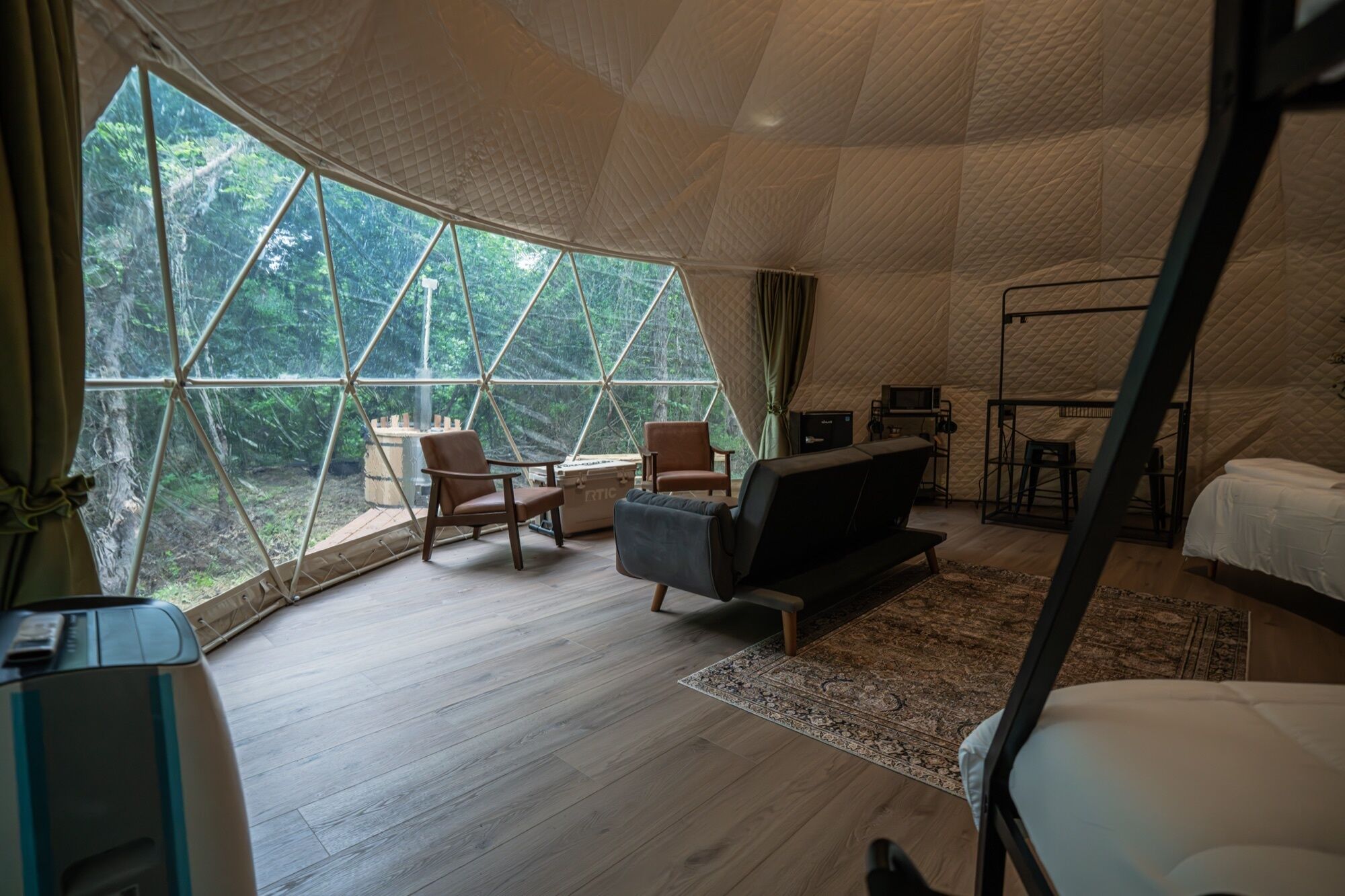 Una habitación amplia con un gran ventanal, cama, sofá, escritorio y una silla.