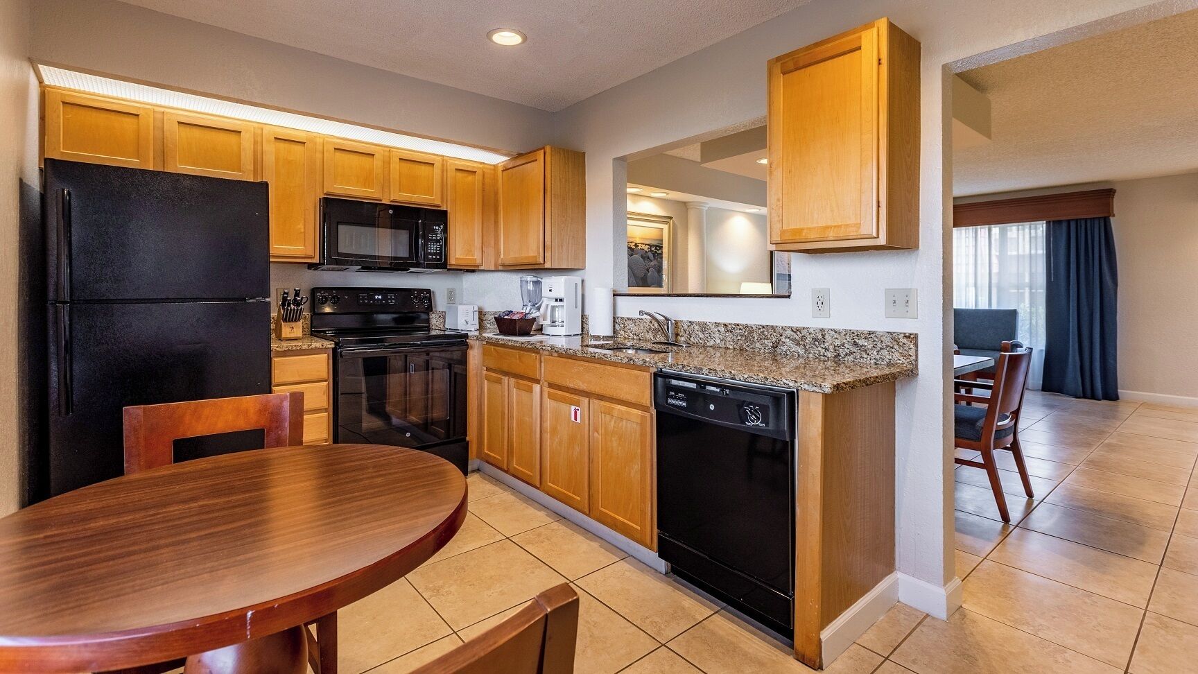 A kitchen with wooden cabinets, a black refrigerator, a microwave, an oven, and a dishwasher.