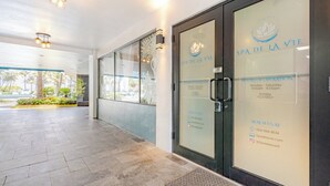 Eingangsbereich eines Spas mit Glastüren, einer Rezeption und einem gefliesten Boden.