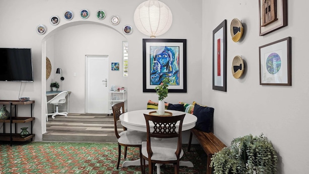 A dining area with a round table, chairs, a TV, and a patterned floor.