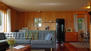 Ett mysigt vardagsrum med en soffa, ett soffbord och en matplats med en stol och ett bord.