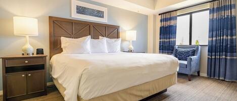 A hotel room with a large bed, two bedside tables, a chair, and a window with curtains.