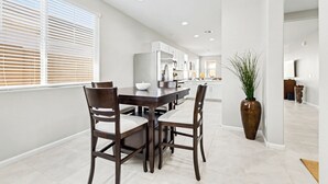 Una cocina moderna con armarios blancos, una mesa de comedor de madera oscura y sillas.
