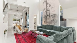 Un salon moderne avec un canapé vert, un tapis rouge et un grand tableau mural.