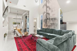 Ein modernes Wohnzimmer mit einem grünen Sofa, einem roten Teppich und einem großen Wandbild.